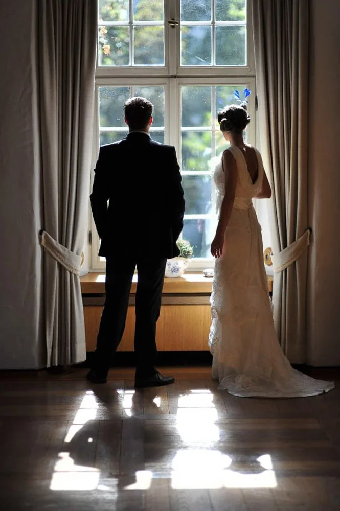 Brautpaar als Silhouette im Fenster – stimmungsvolles Bild vor der Trauung
