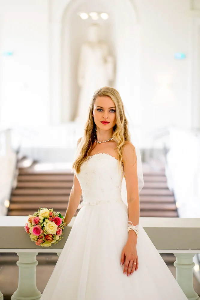 Braut schreitet durch Torbogen – eleganter Moment vor der Trauung